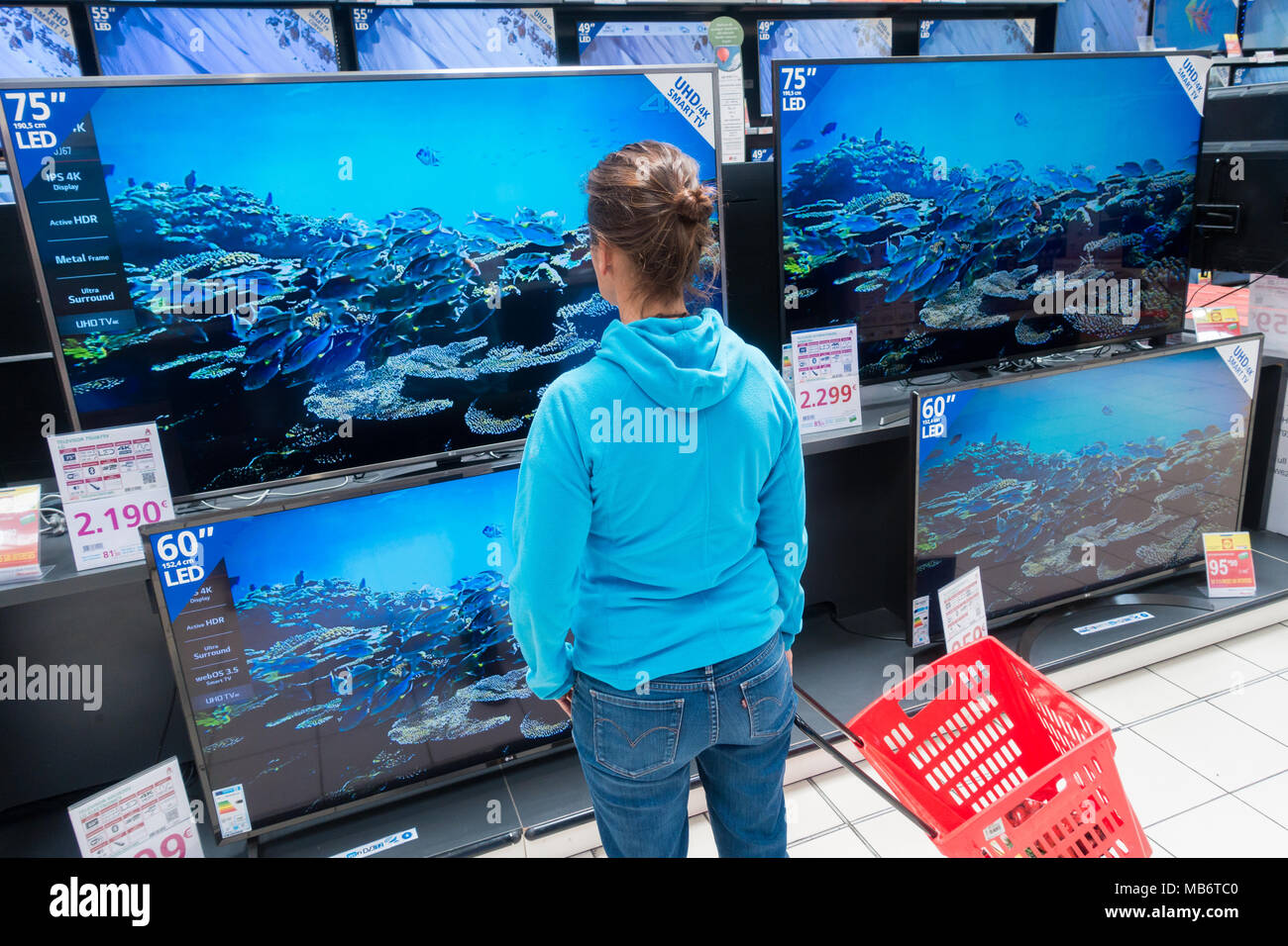 Mujer mirando su nuevo televisor de alta definición 4k pantallas en almacén eléctrico Foto de stock