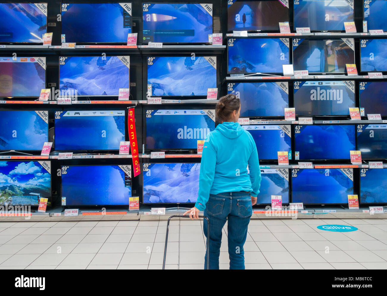 Mujer mirando nuevas pantallas de TV de alta definición en almacén eléctrico Foto de stock