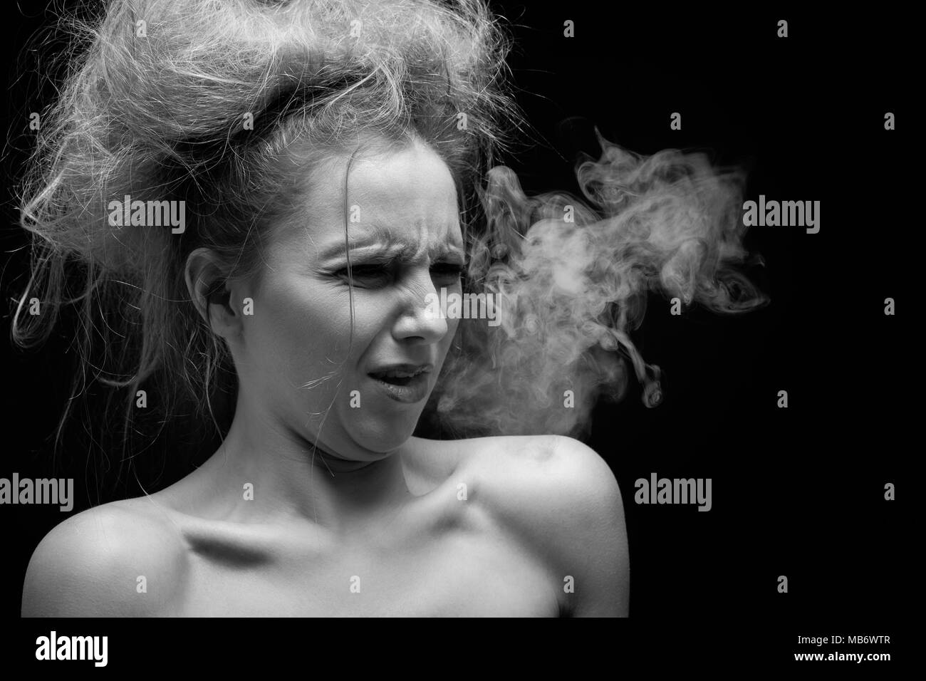 Chica toses del humo del tabaco sobre fondo negro, Monocromo Foto de stock