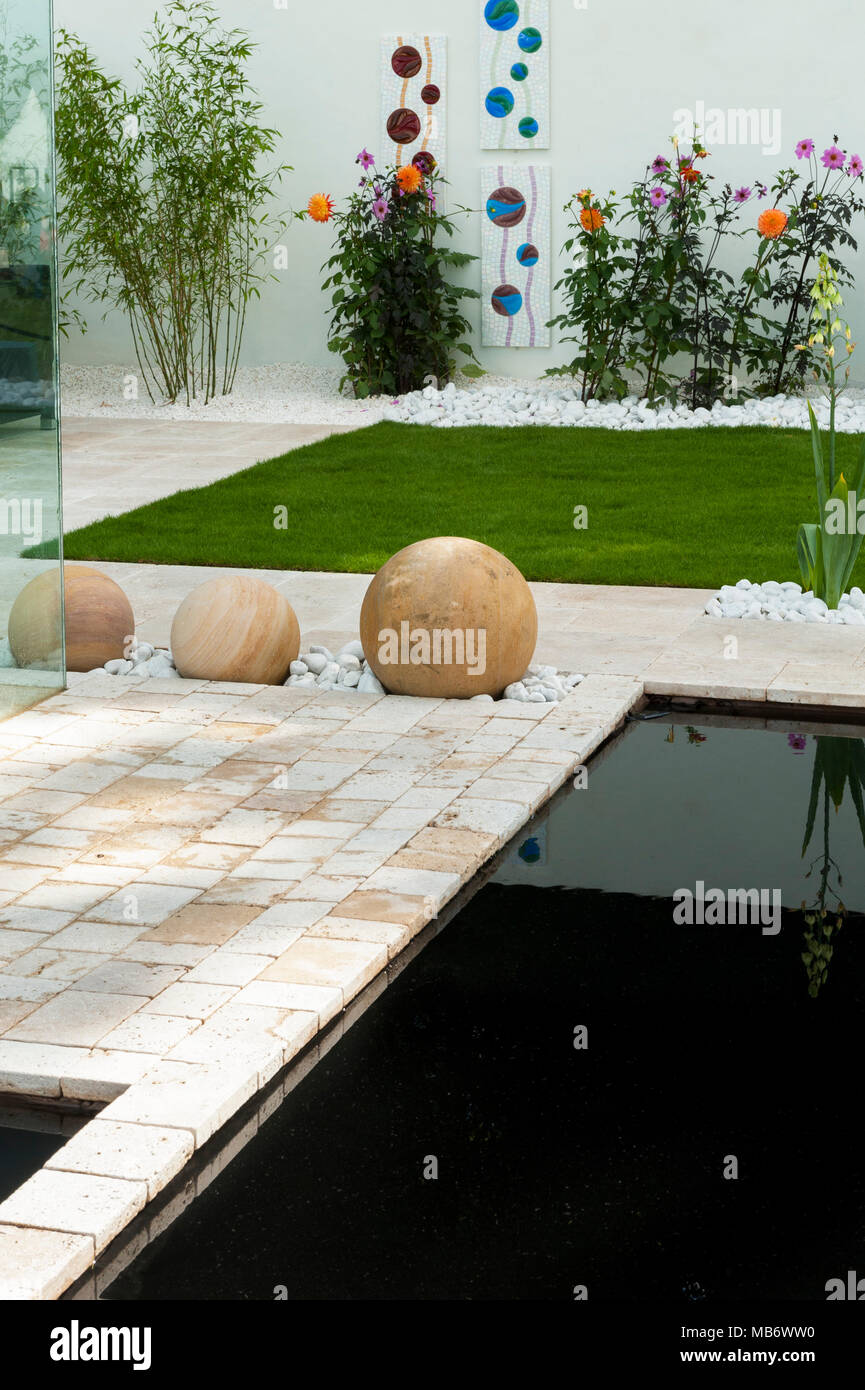 Contemporáneo y minimalista, "respirar" show garden con elegante patio, paredes blancas, un estanque y esferas de piedra - RHS Flower Show, Tatton Park, Inglaterra, Reino Unido. Foto de stock