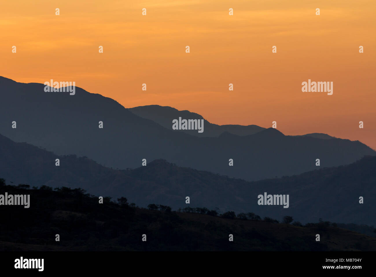 Los tonos naranja y púrpura montañas n un cielo previo al amanecer sobre las montañas al sur de Caldera de Boquete, Panamá en marzo. Foto de stock