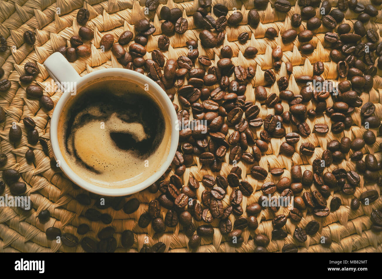 Vista superior de la taza de café y granos de café expreso en una bandeja de servir tejida Foto de stock