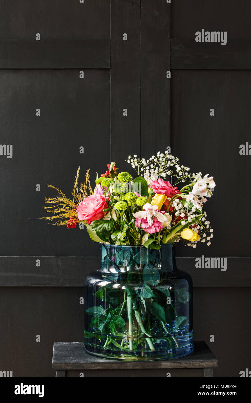 Gran ramo de flores de primavera en un vaso de vidrio contra el fondo negro. Concepto de regalo del día de la madre Foto de stock