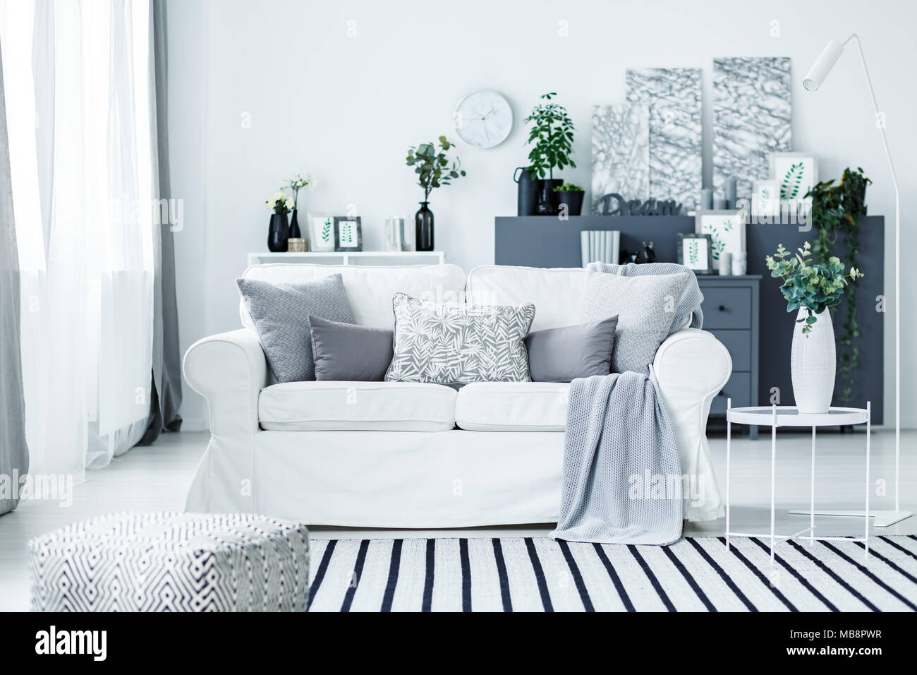 Blanco acogedor sofá y una manta rayas en un elegante salón moderno  interior con muebles de color gris y decoraciones Fotografía de stock -  Alamy