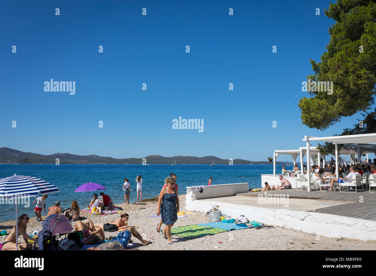 La gente del bronceado en la playa de la ciudad de Zadar, con una terraza de un café al lado, Croacia Foto de stock