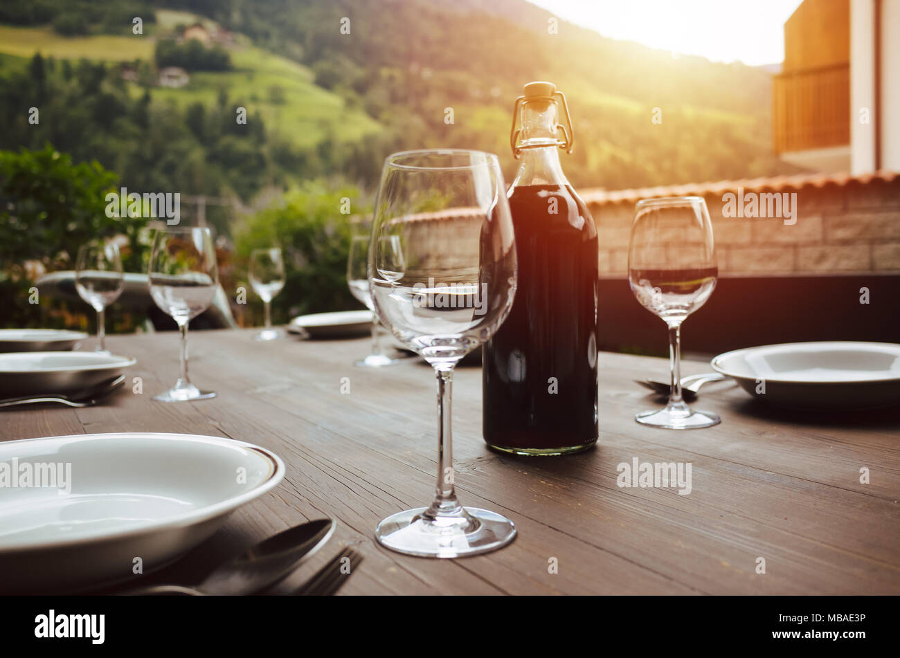 Botella de vino y copas de vino en una mesa al aire libre durante la puesta de sol Foto de stock