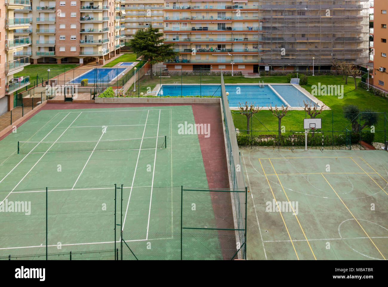 Mirando hacia abajo en una cancha de tenis, cancha de baloncesto y piscinas en Santa Susanna, España. Foto de stock