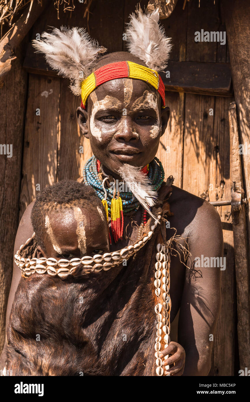 Mujer joven con un niño pequeño con ropa tradicional hecha de goatskin, tribu Karo, las naciones del Sur las Nacionalidades y los pueblos de la región Foto de stock
