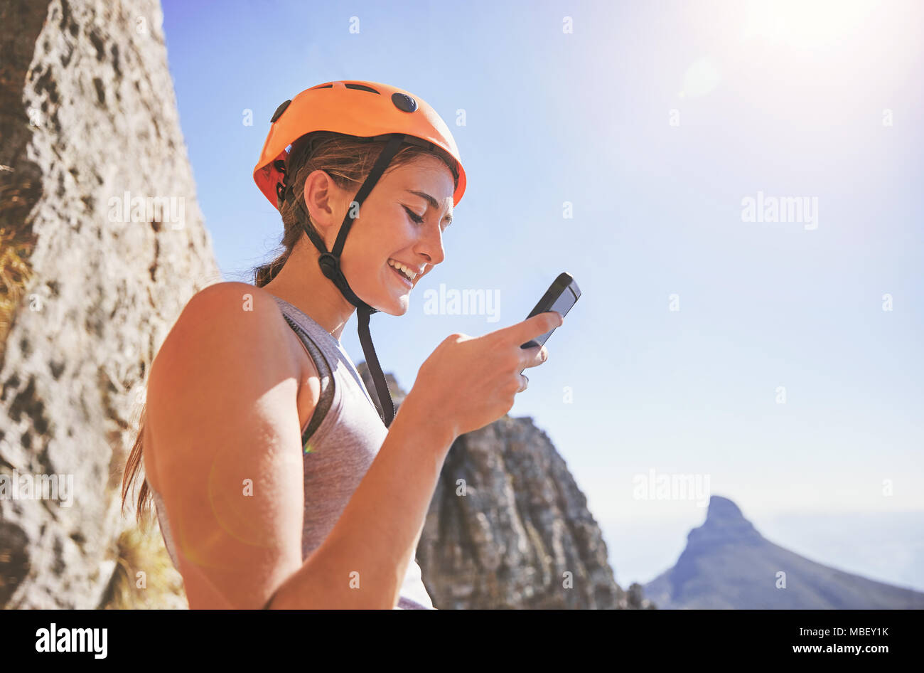 Mujer sonriente escalador utilizando teléfonos inteligentes. Foto de stock