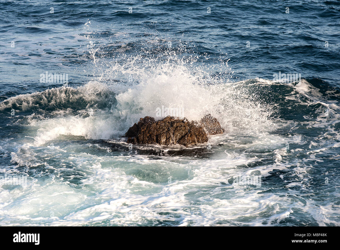 Las salpicaduras de las olas del océano cuando golpeó en una gran piedra en el agua Splash alta Foto de stock