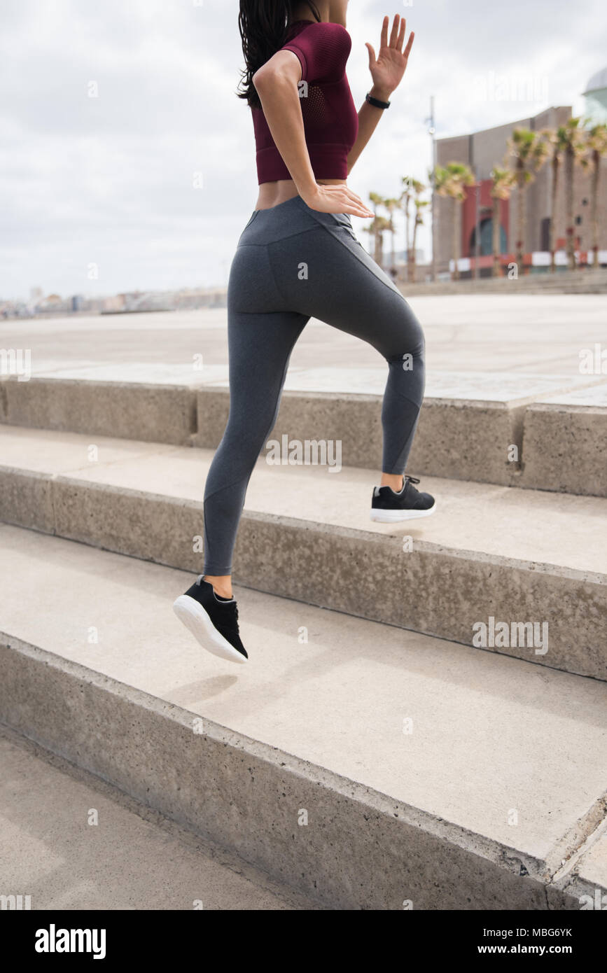 Colocar joven mujer corriendo las escaleras en leotardos, gris y negro  camisa midriff sneakers Fotografía de stock - Alamy