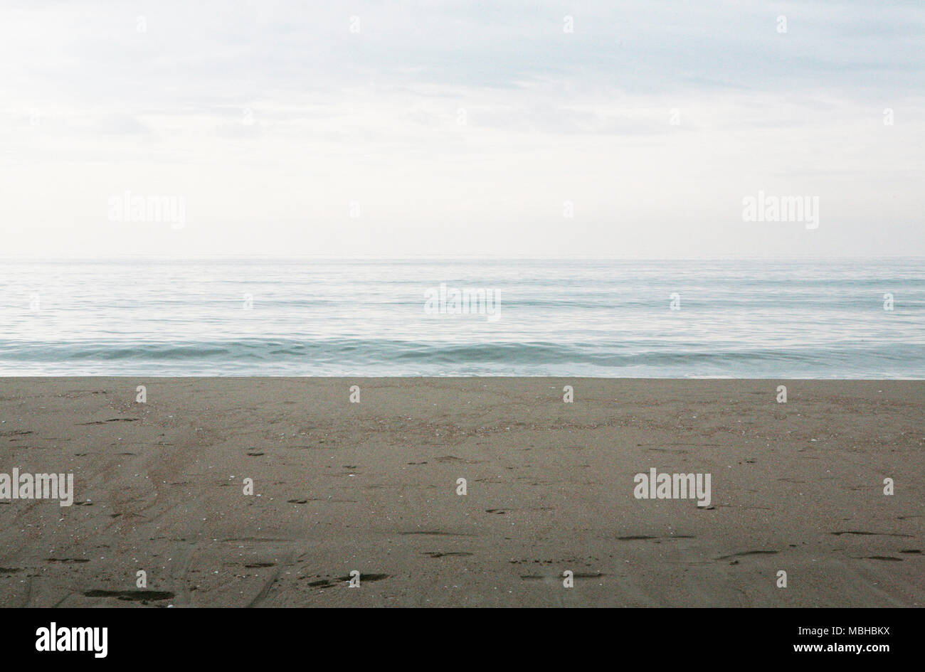Playa de arena y un mar tranquilo, con el cielo claro Foto de stock