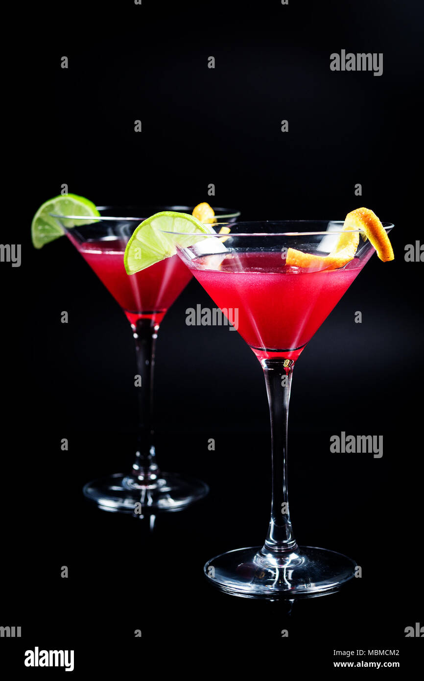 Beber alcohol cocktail Cosmopolitan con cal sobre fondo negro Foto de stock