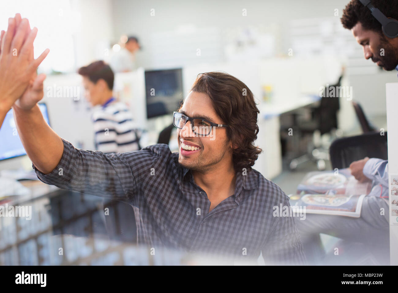 Entusiasta, empresario de alta fiving confiada con su colega en la oficina Foto de stock