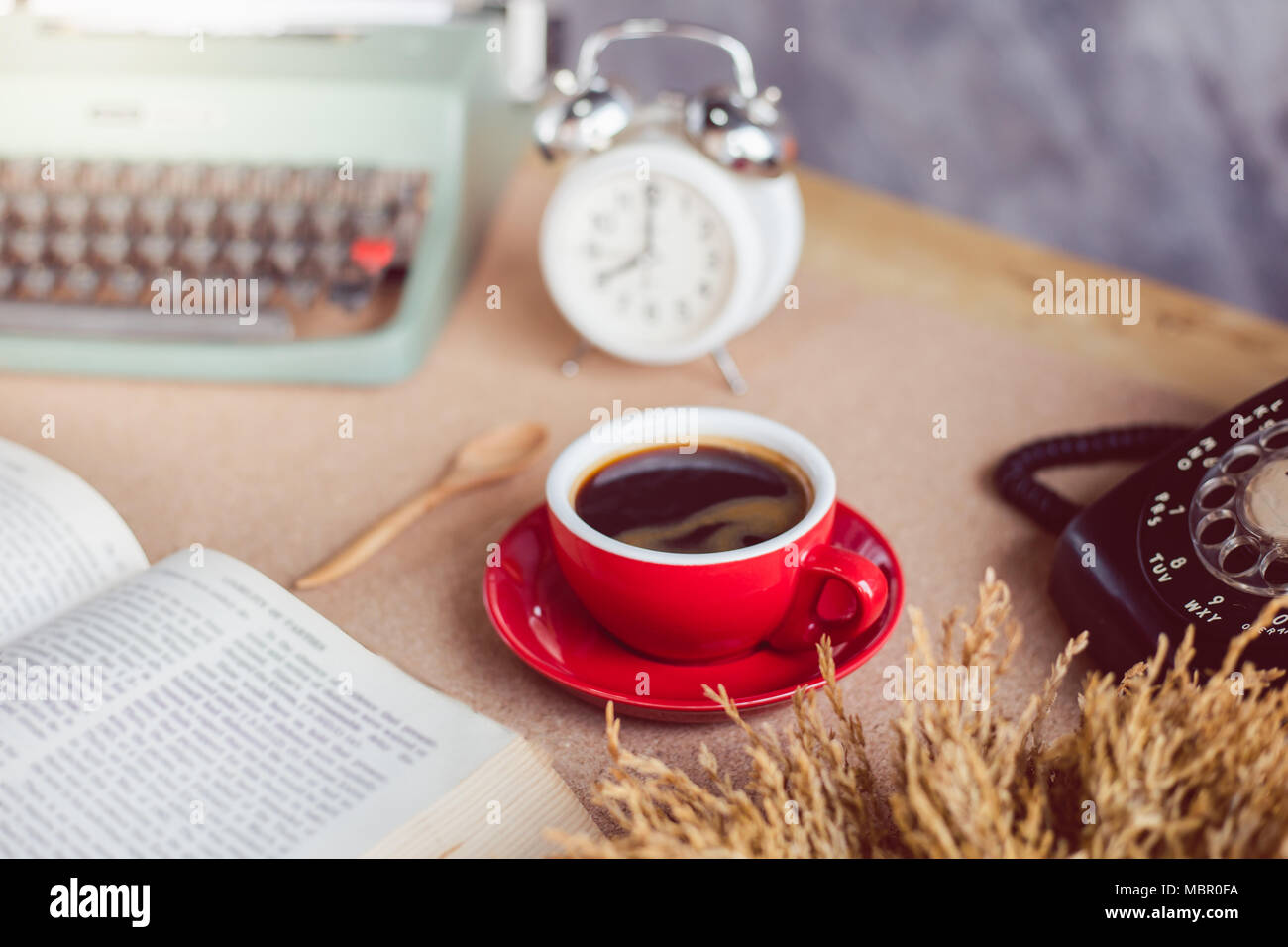 Una taza de café con máquina de escribir y despertador y el libro sobre la  mesa Fotografía de stock - Alamy