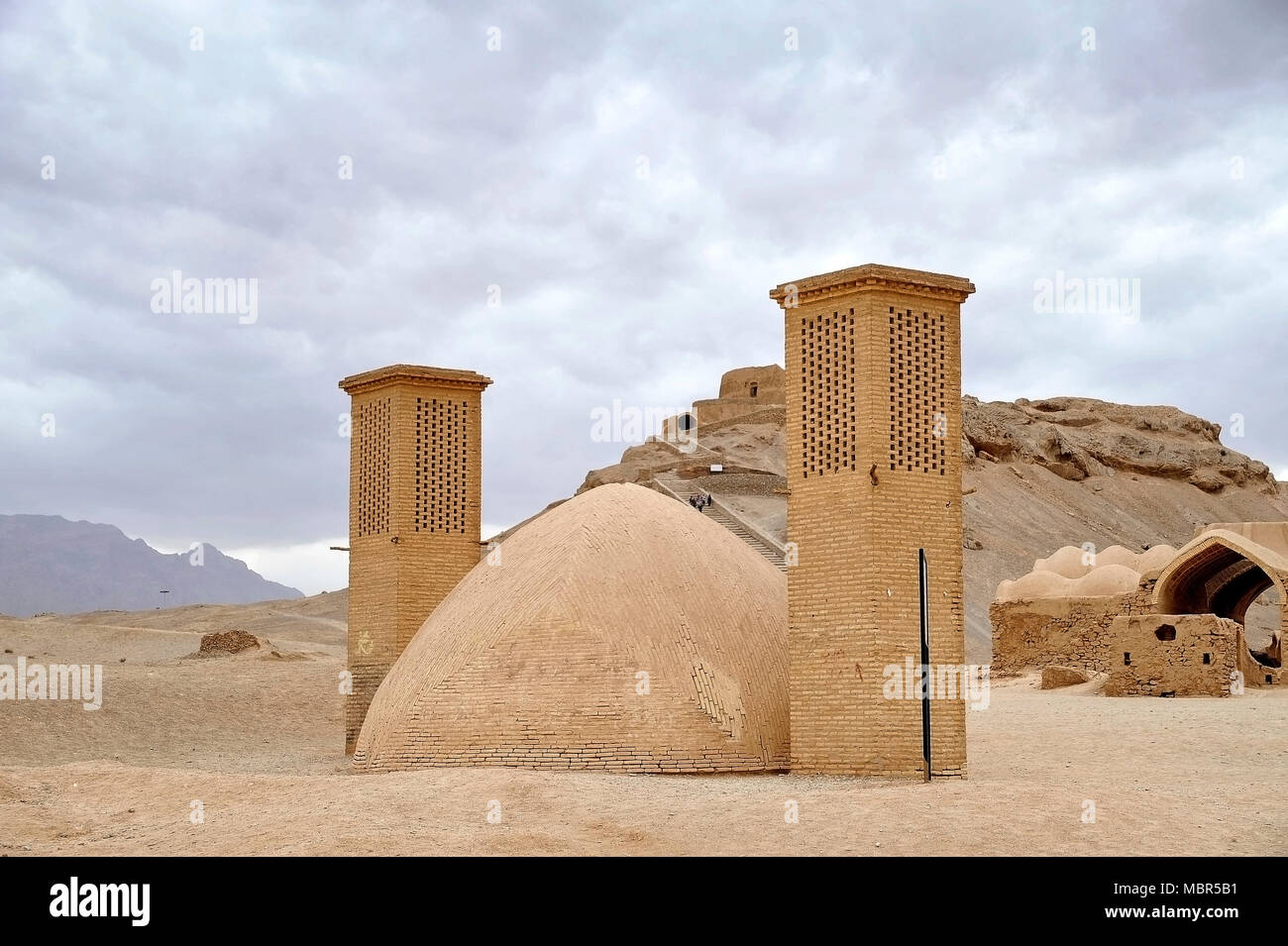 Las torres de viento utilizados como un sistema de refrigeración natural para el depósito de agua en la arquitectura tradicional iraní. Torre de silencio en el fondo. Yazd, Irán Foto de stock