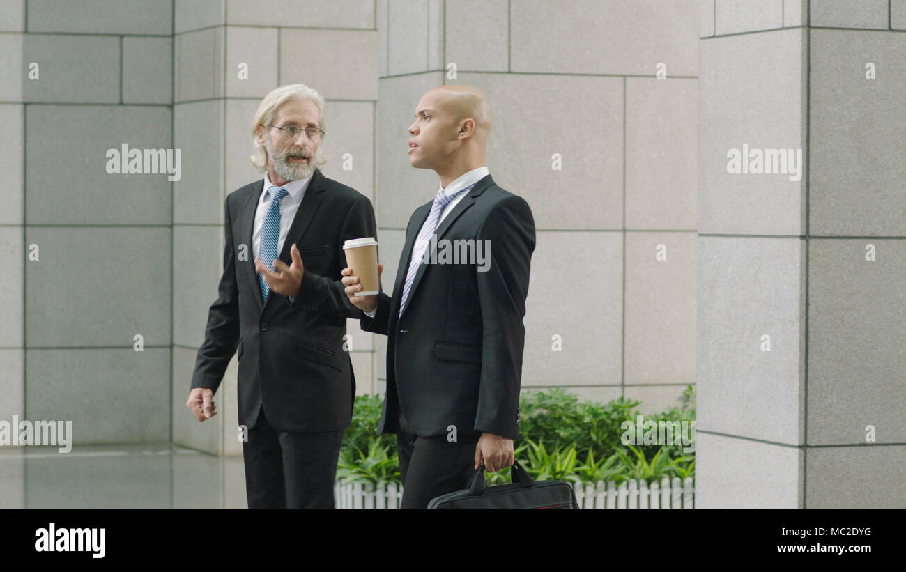 El Cáucaso y ejecutivos de negocios latinos hablando mientras camina en el moderno edificio de oficinas. Foto de stock