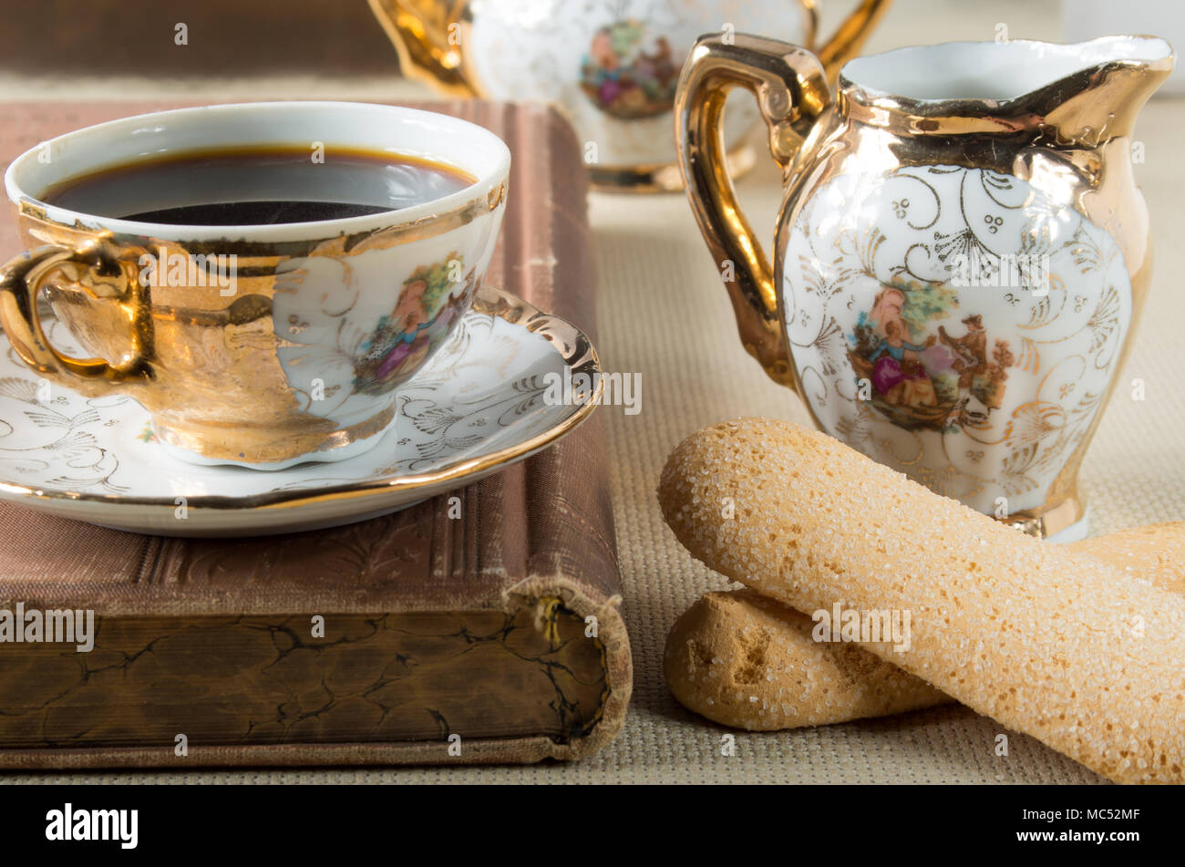 El café de la mañana y galletas Savoiardi sobre la mesa con un conjunto de platos clásicos de la porcelana antigua alemán del siglo XIX Foto de stock