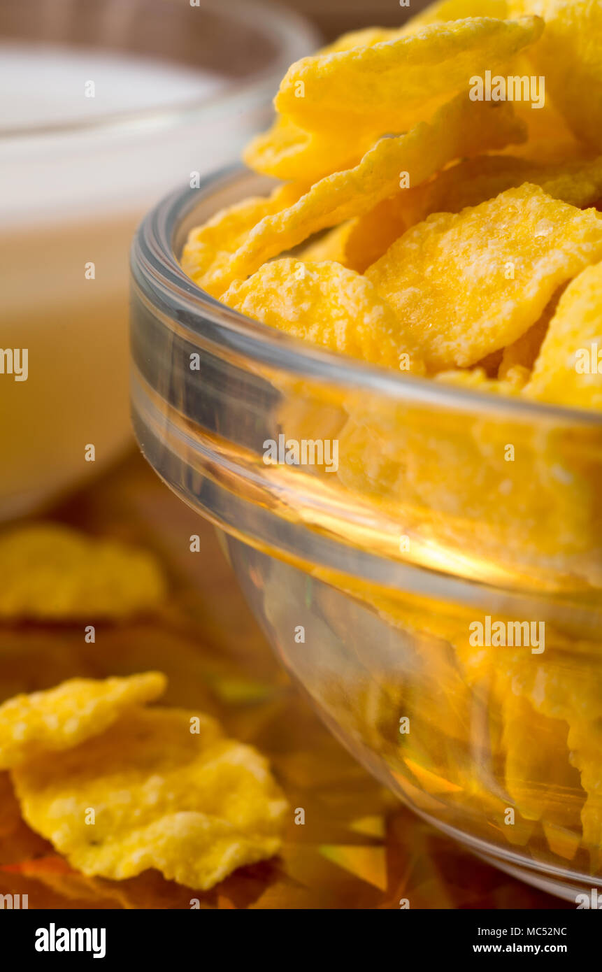 Ingredientes para el desayuno. Desenfoque de imagen borrosa y copos de maíz seco en un recipiente transparente closeup con poca profundidad de enfoque. Foto de stock
