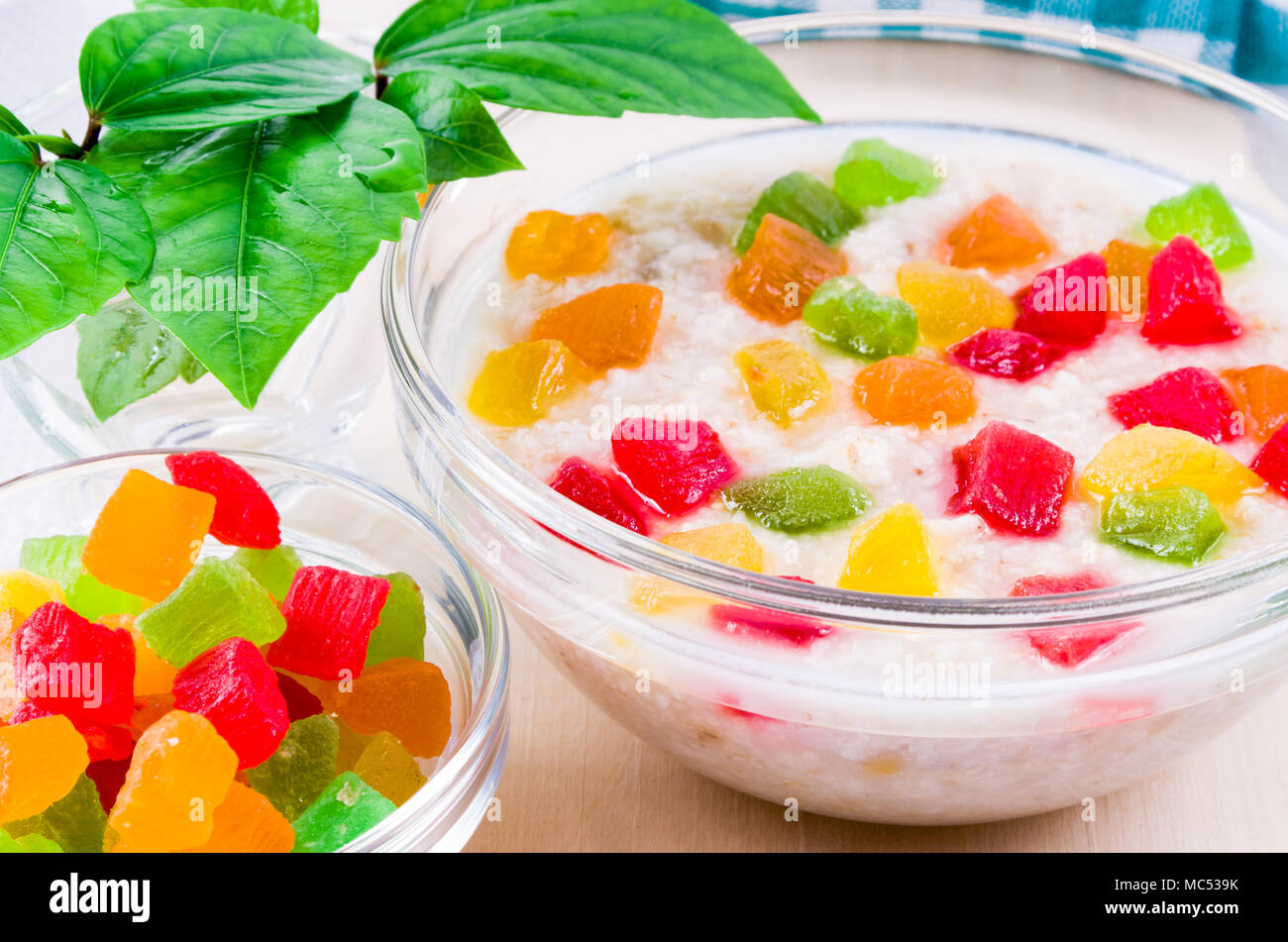 Avena saludables de cerca con coloridas frutas confitadas para desayunar está iluminado por la luz solar desde la ventana Foto de stock