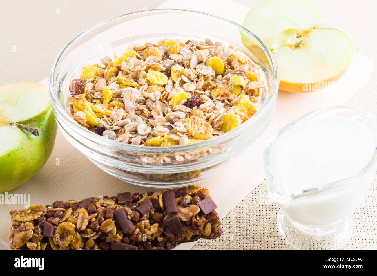 Muesli en un recipiente de cristal, la leche y la manzana fresca para el desayuno Foto de stock