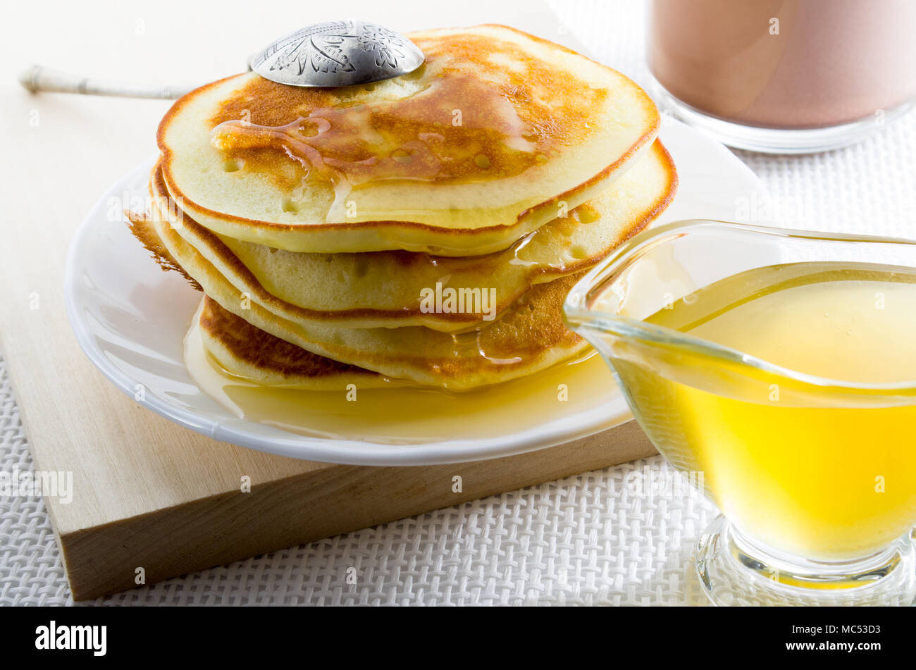 Tortitas con miel y vintage Silver Spoon en una placa blanca para un desayuno dulce con poca profundidad de campo. Foto de stock