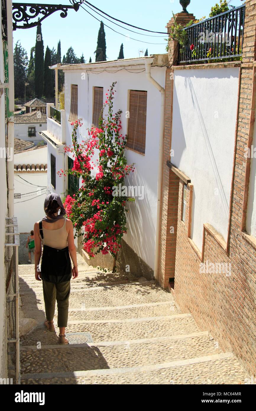 Mujer con un pañuelo bajando las escaleras en el barrio de Albaicín de Granada, Andalucía, España Foto de stock