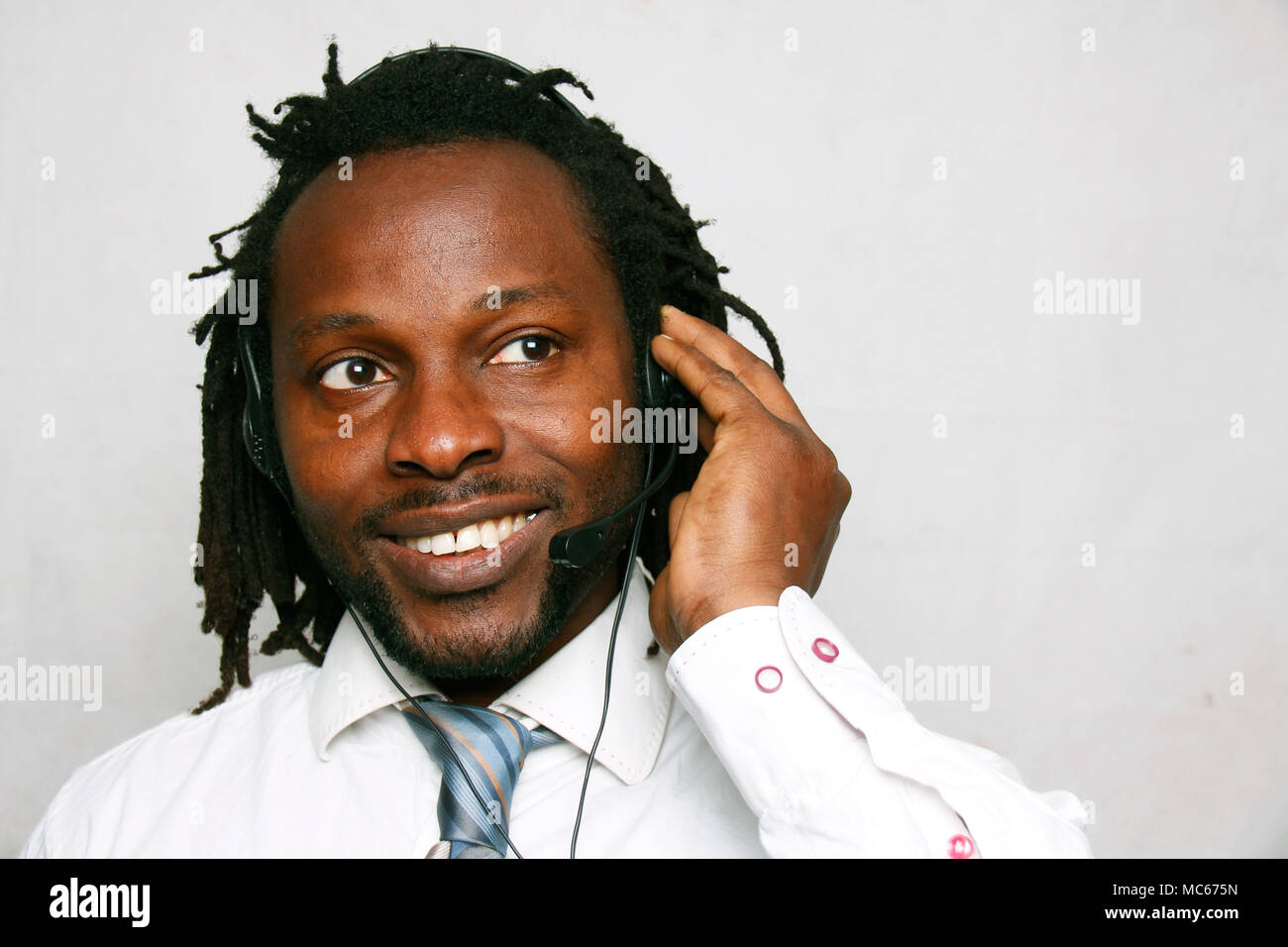 Un hombre de negocios sonriendo sonriendo y llamando con los auriculares, el servicio de atención al cliente Foto de stock