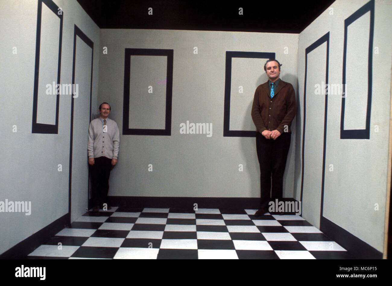 Las ilusiones. Dos hombres de la misma altura de pie en una sala de Ames diseñados para crear la ilusión óptica que cambia la altura relativa de los hombres. Foto de stock