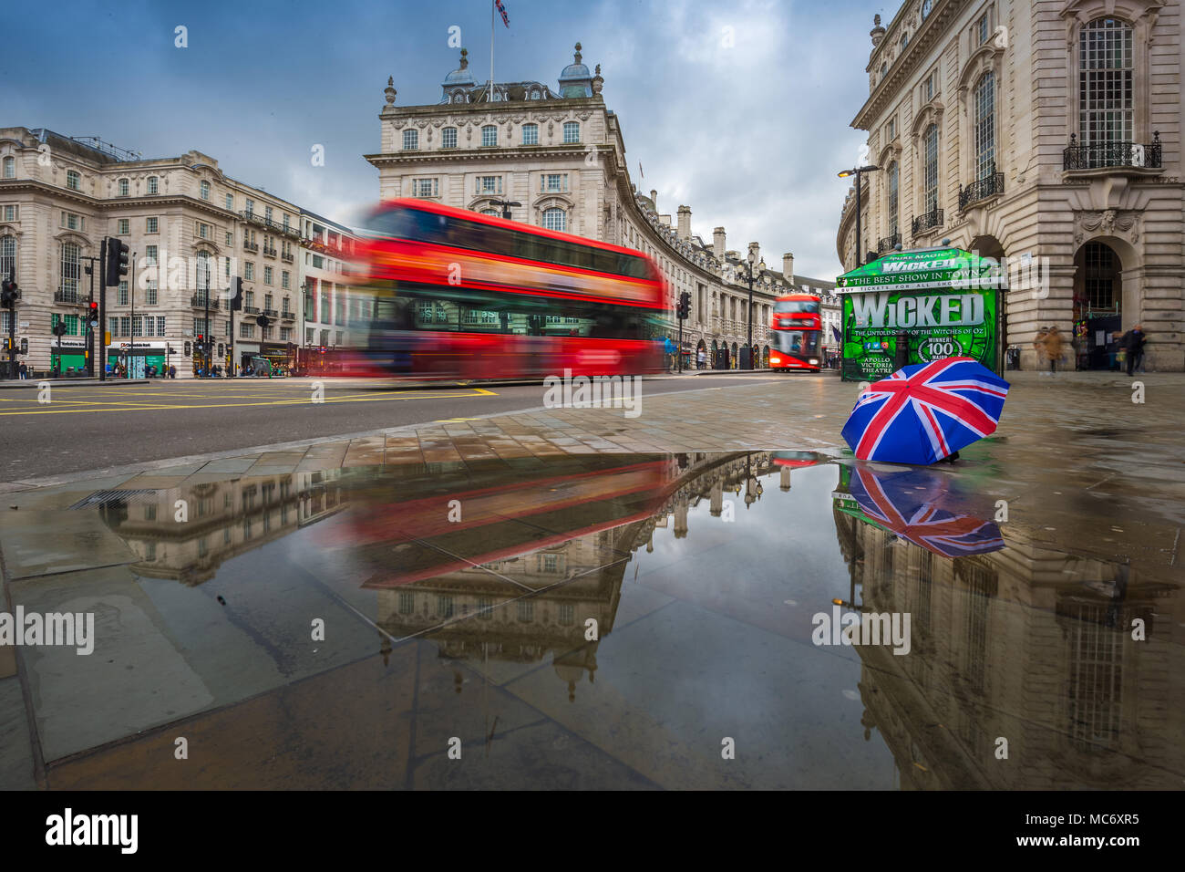 Londres, Inglaterra - 03.15.2018: reflexión de autobuses de dos pisos de  color rojo sobre el movimiento en Piccadilly Circus con british paraguas.  Piccadilly Circus es el m Fotografía de stock - Alamy