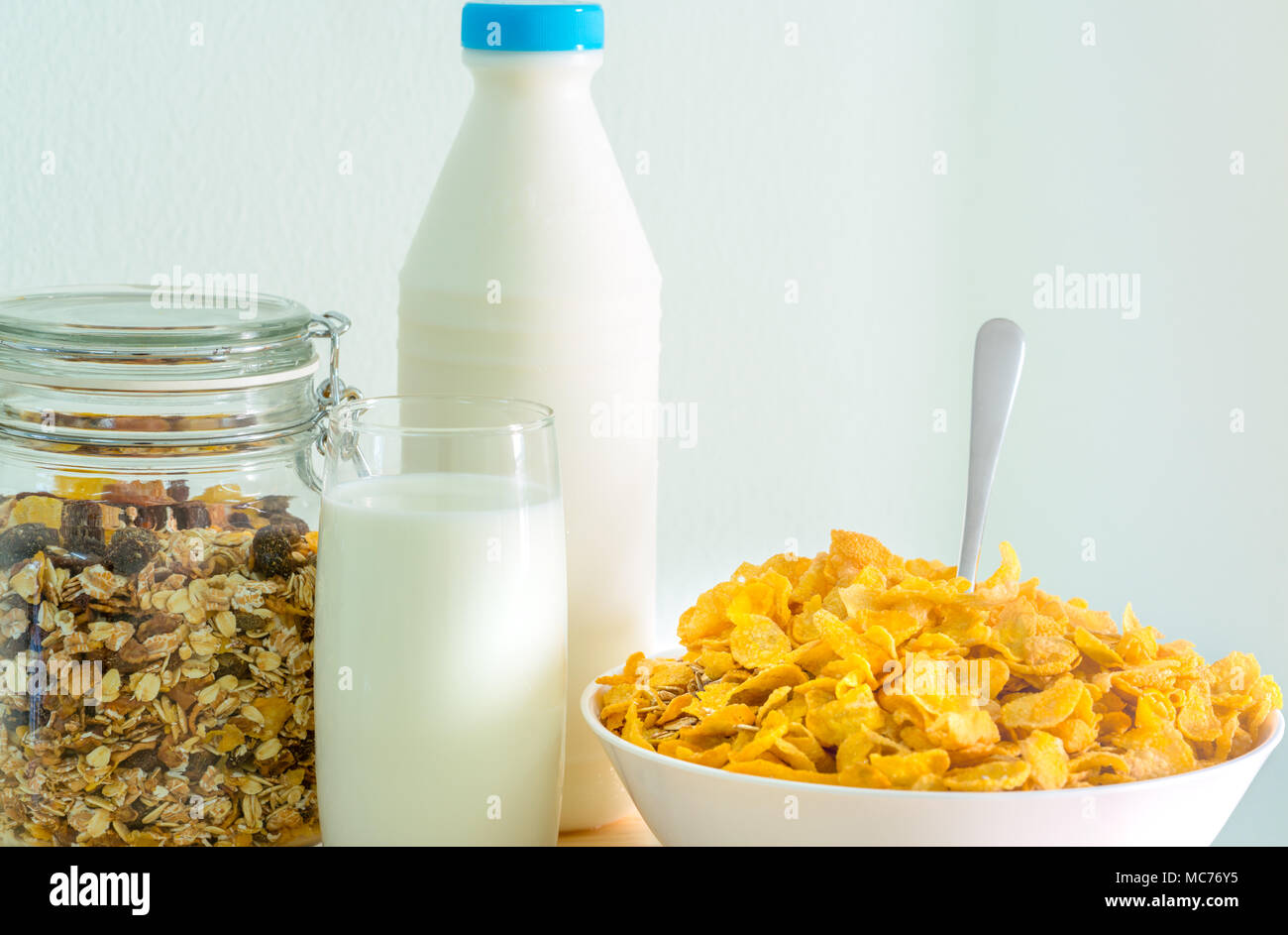 Un vaso de leche y botella con etiqueta en blanco poner sobre la mesa de  madera cerca de tazón de cereales con cuchara. Desayuno para niños  alimentos calcio antes de ir a