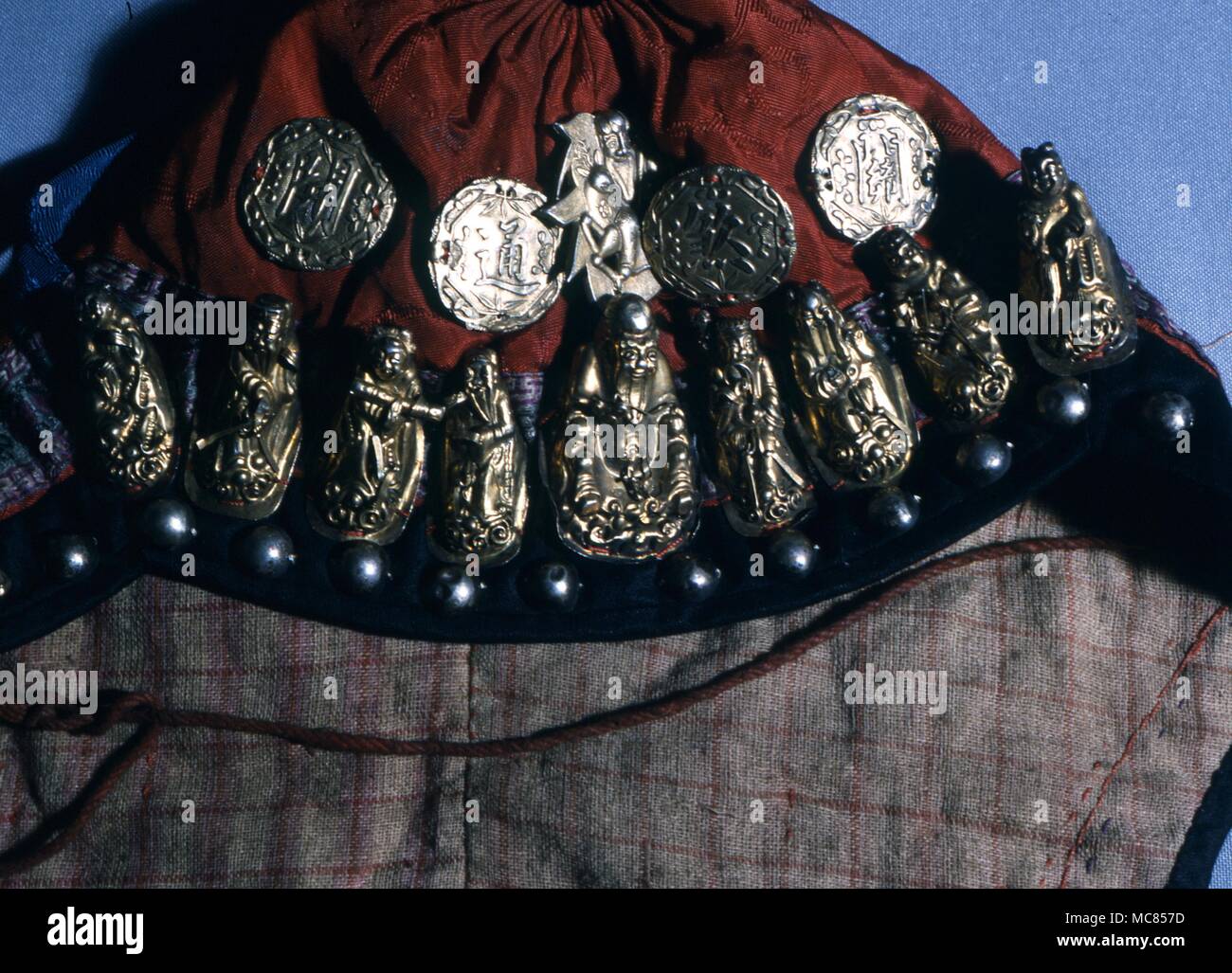 Imágenes de metal crudo amuleto de los Ocho Inmortales chinos y amuletic monedas, fijada en la parte delantera de un niño en el sombrero, desde el norte de China. Ahora en una colección privada en Hong Kong. Los amuletos e inmortales están utilizadas para protección Foto de stock
