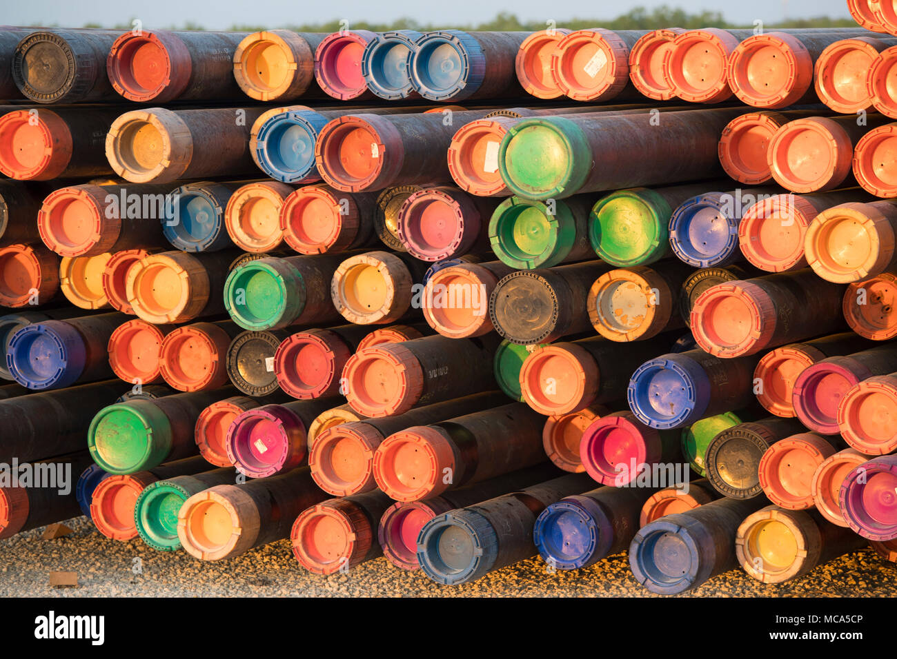Tubo de perforación con tapas de color sentarse apilados en un patio en la  autopista 16 cerca de los campos petroleros en el Eagle Ford shale jugar en  McMullin County, al sur