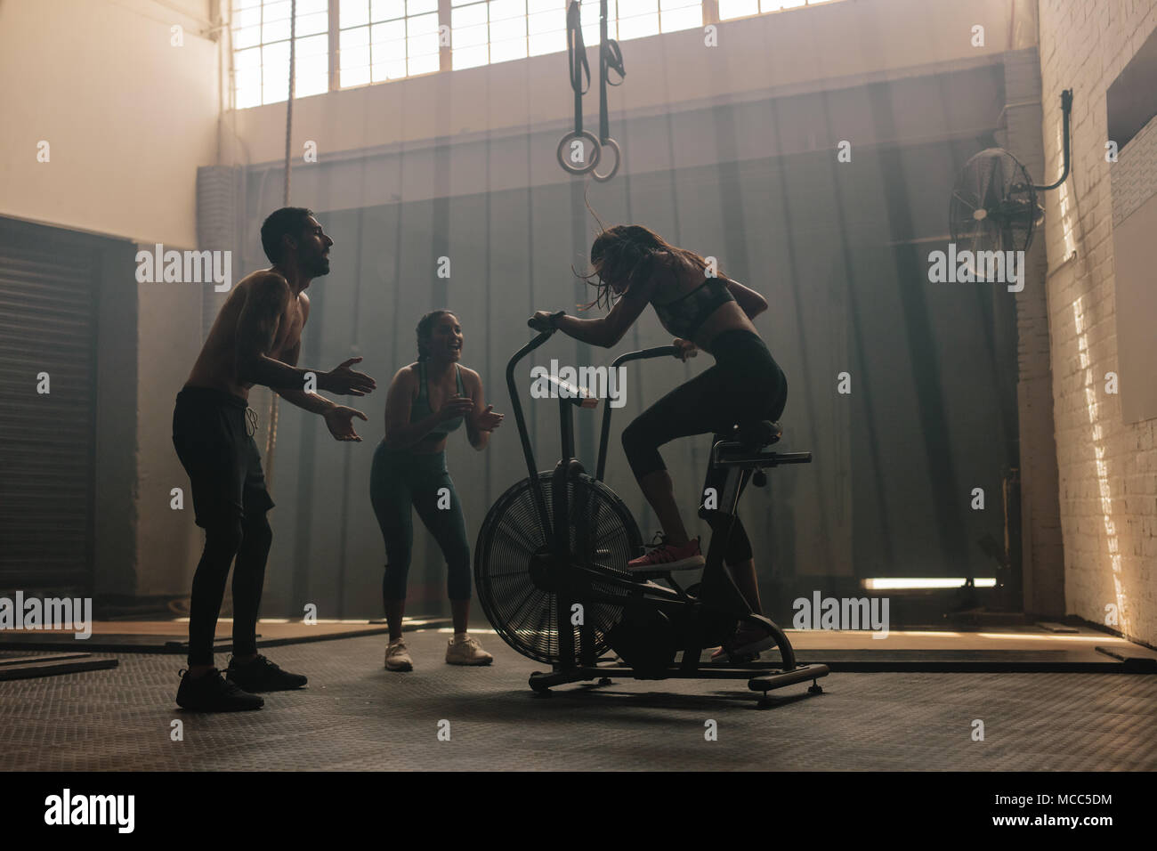 La mujer ejerce sobre el aire en bicicleta en el gimnasio con amigos  motivadoras. Hembra por aire en bicicleta para entrenar en el gimnasio  entrenamiento cruzado con amigos Fotografía de stock -