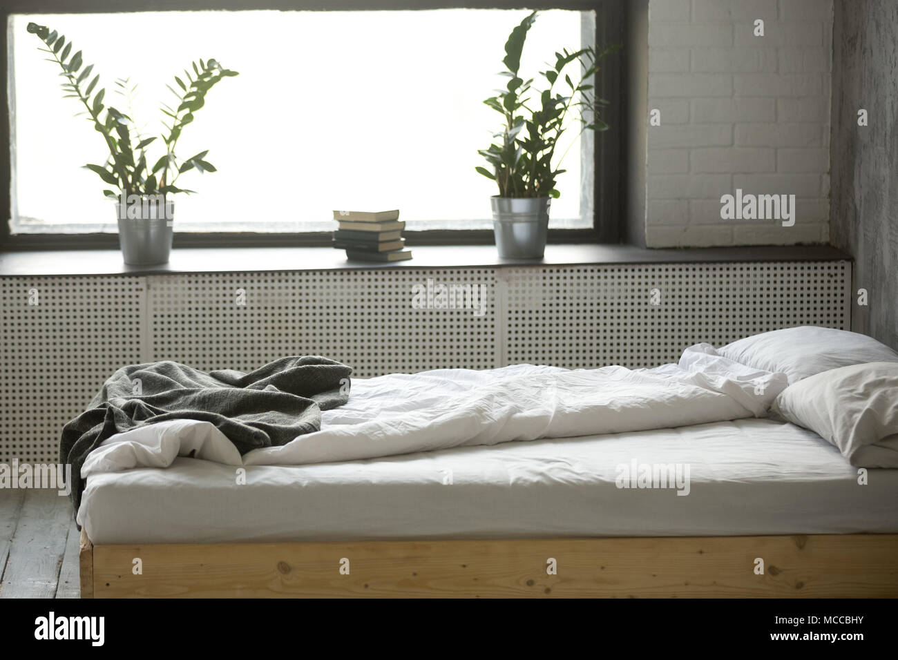 Se deshacen desordenada cama doble para dos personas con ropa de cama de  lino de hoja arrugada cerca de la ventana en modernas y confortables  habitaciones con un diseño interior gris nadie,