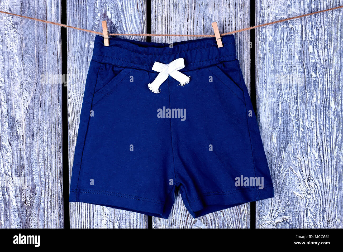 Tendedero con colgantes cortos niños. Childs pantalones de secado cuerda en gris de fondo de madera Fotografía de stock - Alamy