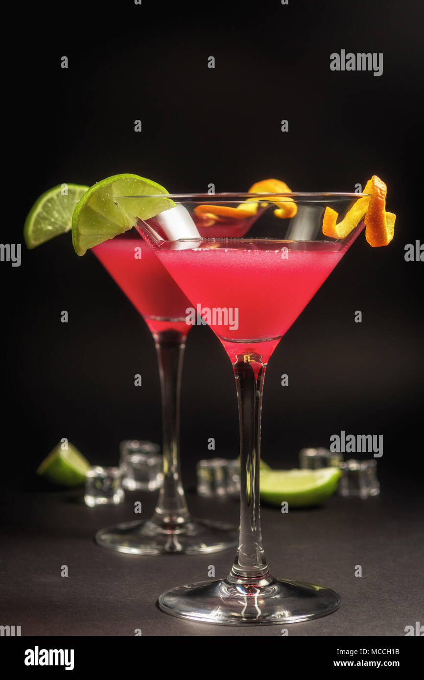 Beber alcohol cocktail Cosmopolitan con cal sobre fondo negro Foto de stock