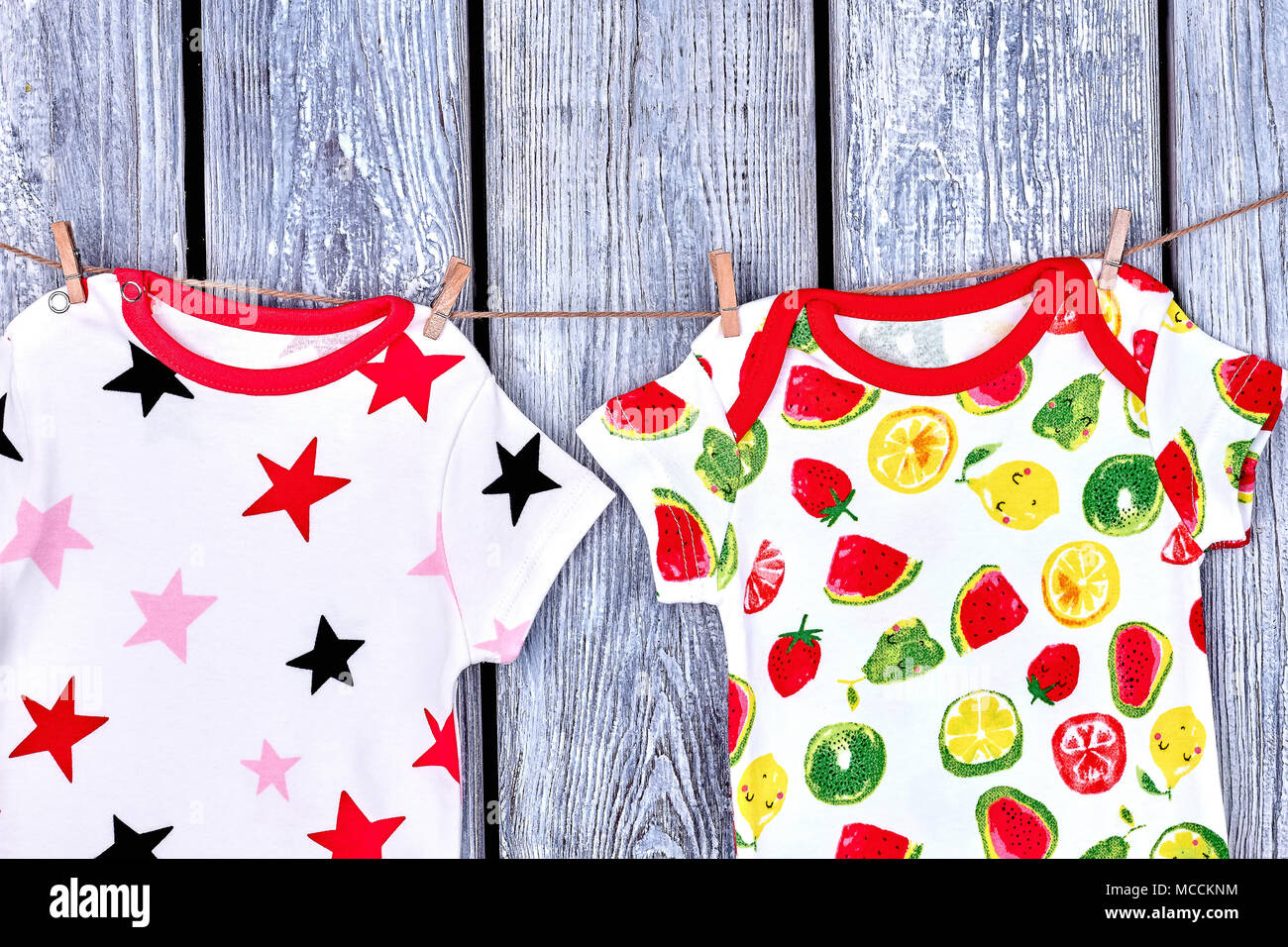 Los niños modernos ropa colgando de la cuerda. Los bebés vestidos impresos  de secado en tendedero sobre fondo de madera vieja Fotografía de stock -  Alamy