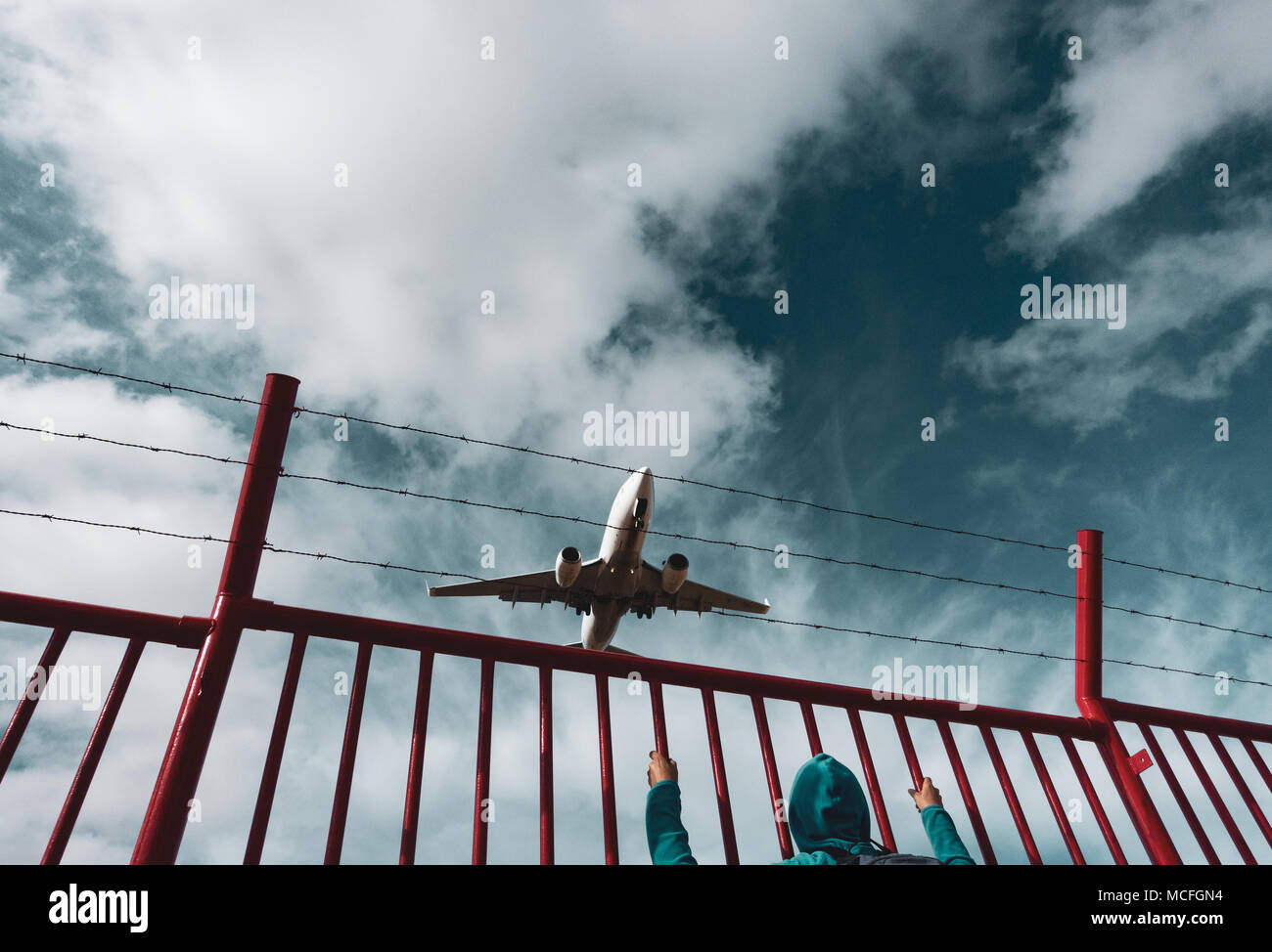 Una mujer mirando un avión/avión desde detrás del perímetro de alambre de púas, cerca de la frontera. Imagen conceptual: Rusia Ucrania Conflicto, zona de exclusión aérea, crisis de refugiados. Foto de stock