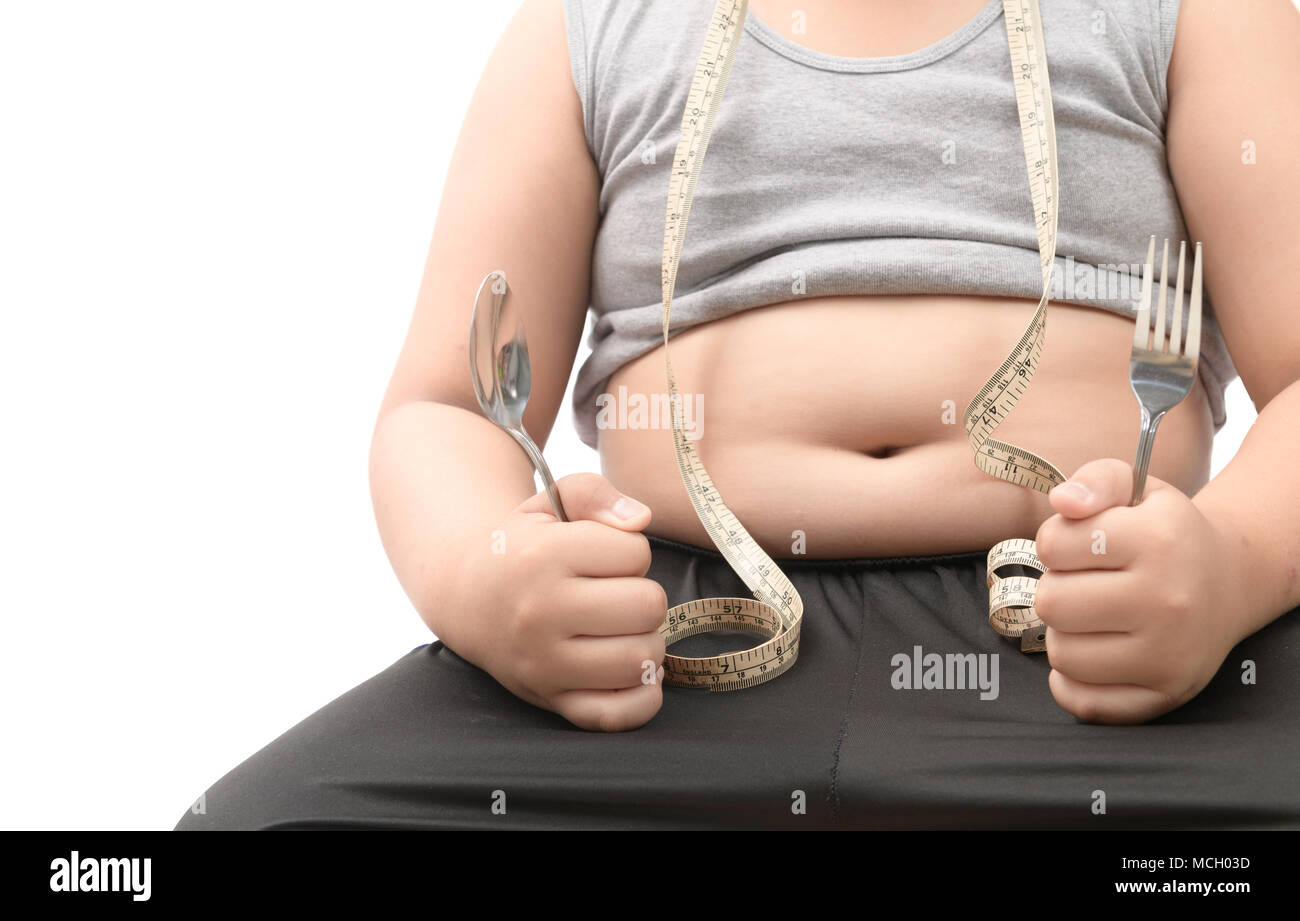 Obeso Fat Boy holding tenedor y cuchara aislado sobre blanco, dieta para perder peso y concepto saludable Foto de stock