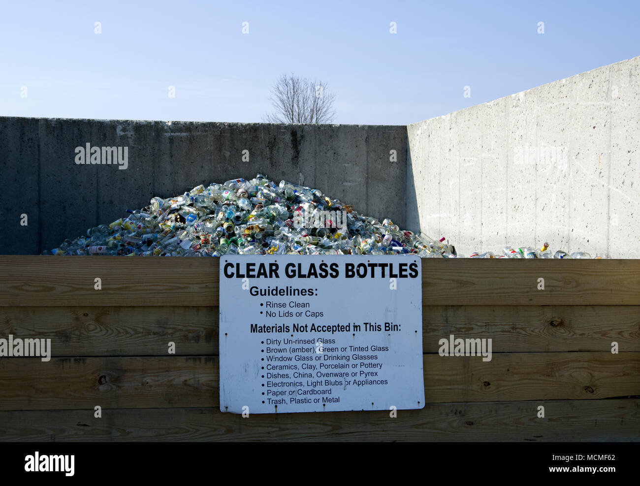 Botellas de vidrio transparente en la bandeja de recolección de reciclaje comunitario Foto de stock