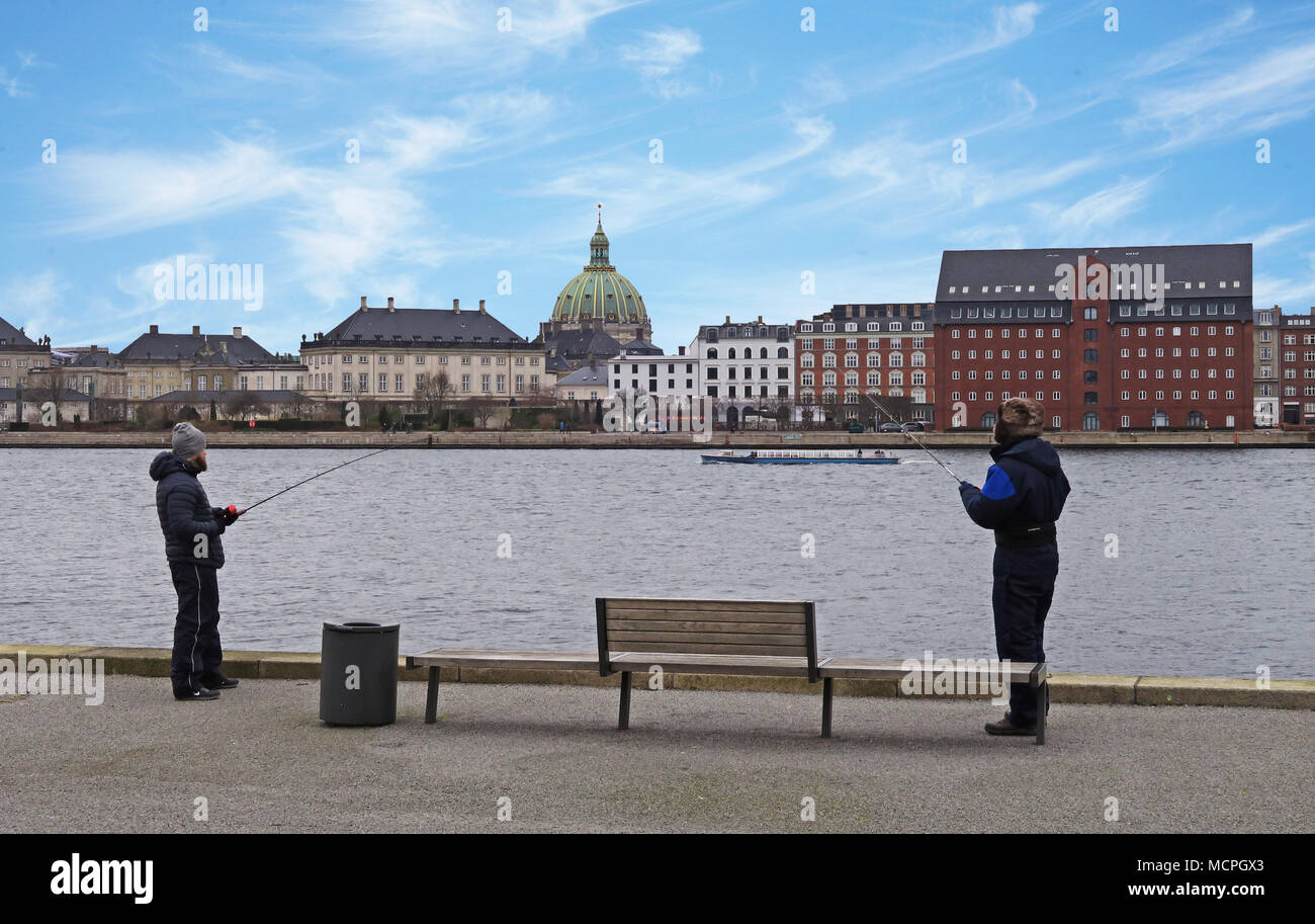 Dos hombres pescando en el puerto de Copenhague con Amalienborg en segundo plano. Foto de stock