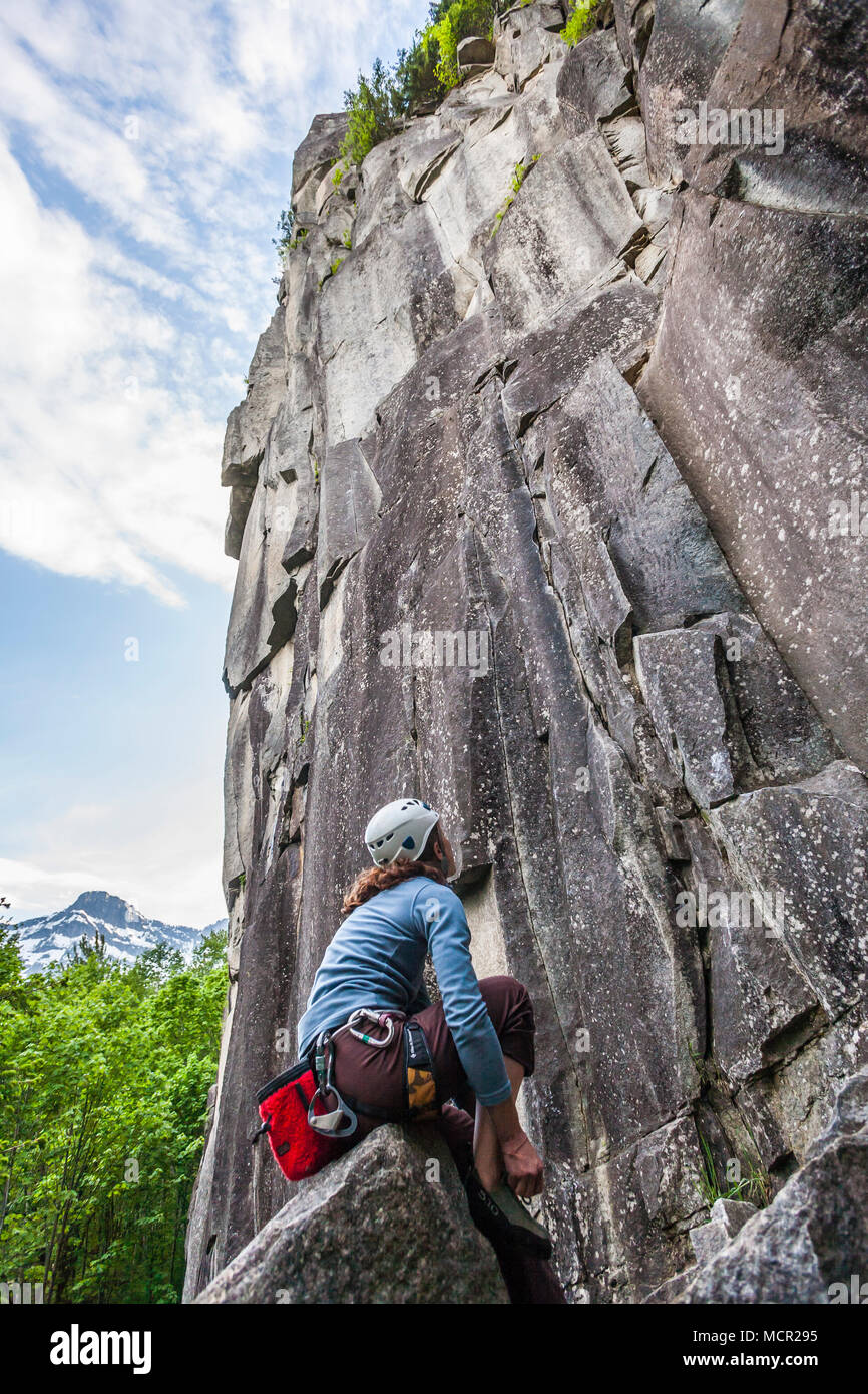 Una mujer poniendo en sus zapatos escalar y mirando la cara de la roca que estaba a punto de Index área de escalada, de Washington, Estados Unidos Fotografía de