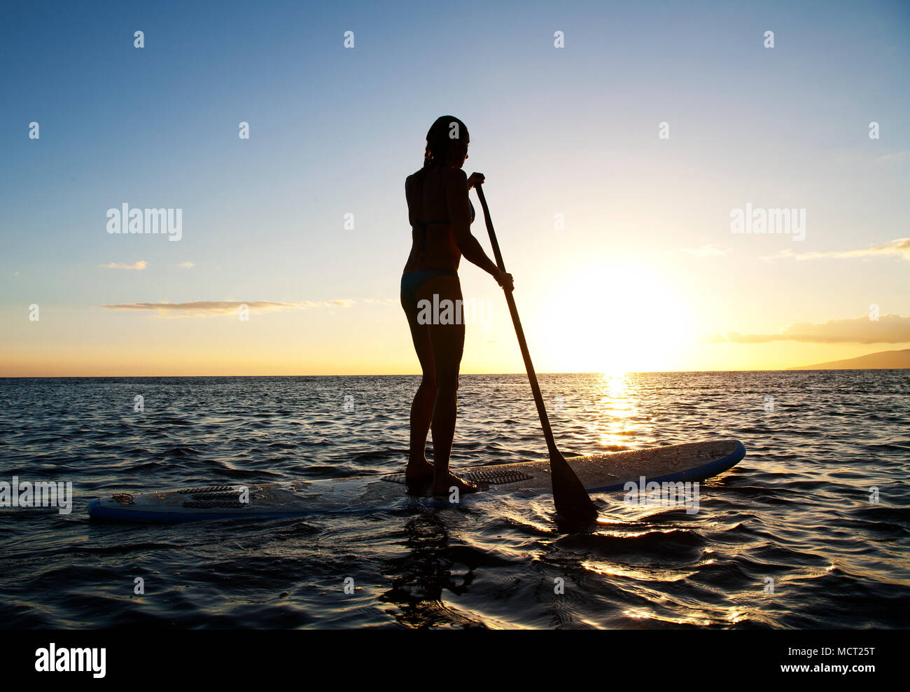 Stand up femenino remando en el atardecer en Olowalu, Maui, Hawaii. Foto de stock