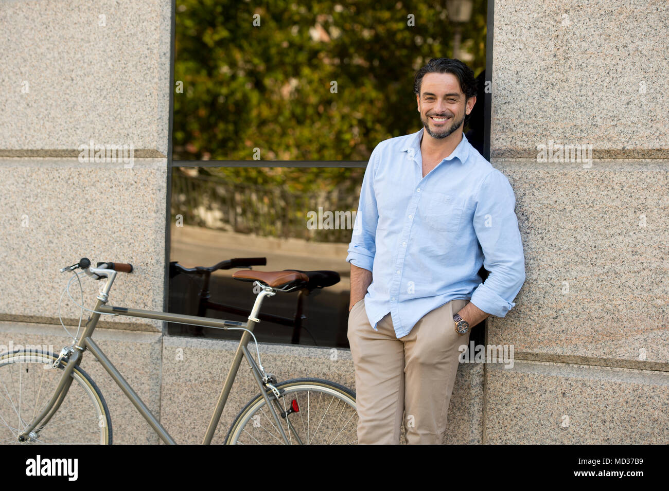 Feliz joven atractivo hombre latino ropa de moda casual sonriendo alegre montando bicicleta vintage cool en el estilo vida moderno urban styl Fotografía de stock - Alamy