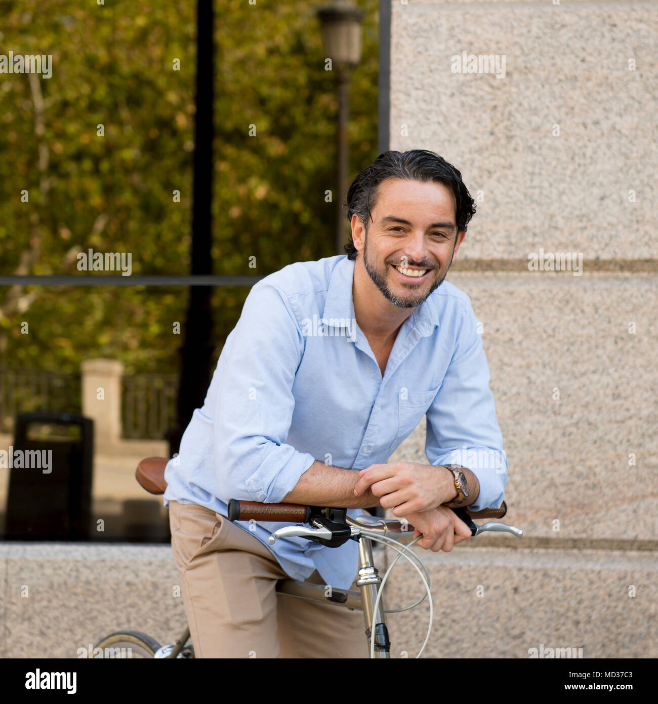 Feliz joven atractivo hombre latino ropa de moda casual sonriendo alegre montando bicicleta vintage cool en el estilo vida moderno urban styl Fotografía de stock - Alamy