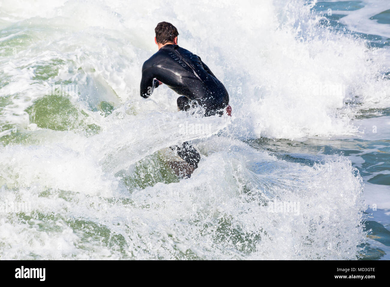 Bournemouth, Dorset, Reino Unido. El 18 de abril de 2018. El clima del REINO UNIDO: olas grandes, ofrecen condiciones ideales para la práctica del surf en la playa de Bournemouth en el día más caluroso del año hasta la fecha. Surfer en acción sobre surf montando una onda. Foto de stock