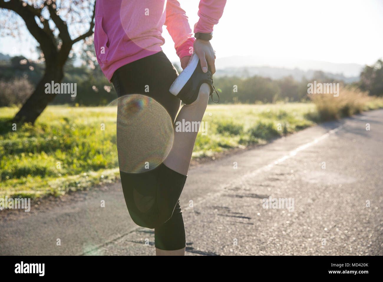 Mujer joven ejercer en entorno rural, el estiramiento de la pierna, bajo la sección Foto de stock