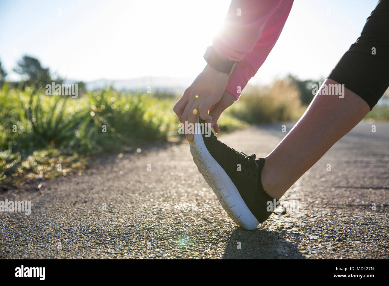 Mujer joven ejercer en entorno rural, el estiramiento de la pierna, bajo la sección Foto de stock