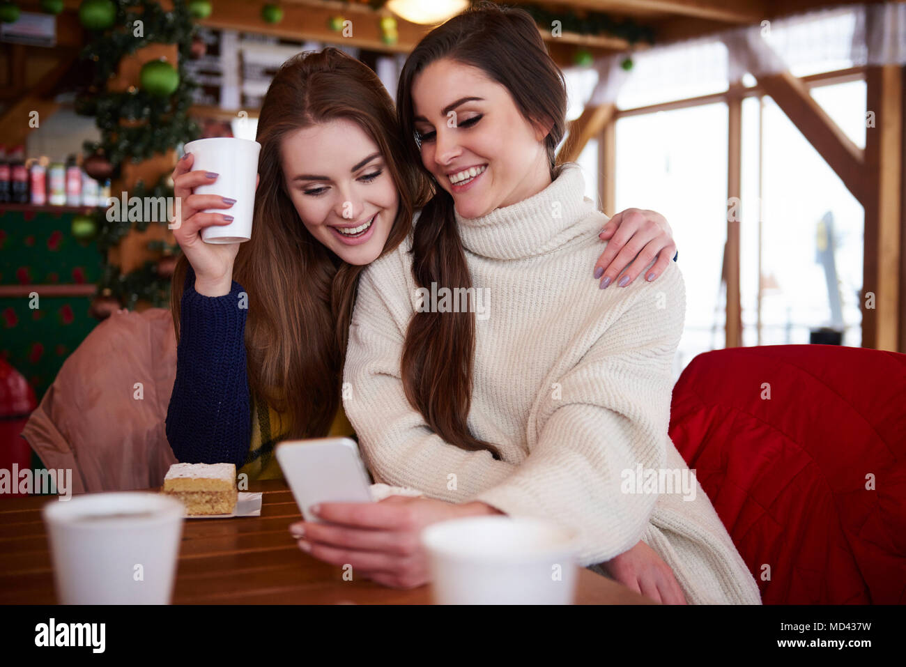 Las mujeres jóvenes sonriendo a través de mensaje de texto por teléfono móvil Foto de stock